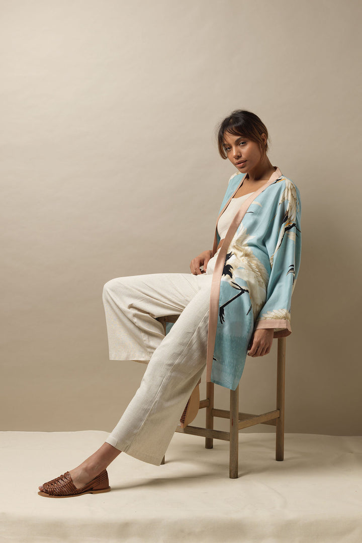 The Stork Crane Sky Blue Collar Kimono is worn here with cream linen trousers and a cream vest top, letting the sky blue colour stand out. 