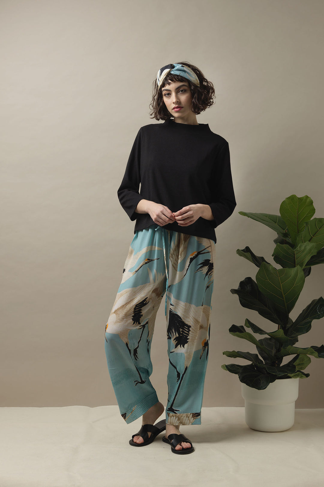 The One Hundred Stars Stork Sky Blue Crepe Lounge Pants are styled here with a black jumper and black sandals, plus accessorised with a Stork Sky Blue Headband. Creating a luxurious but comfortable day look. 